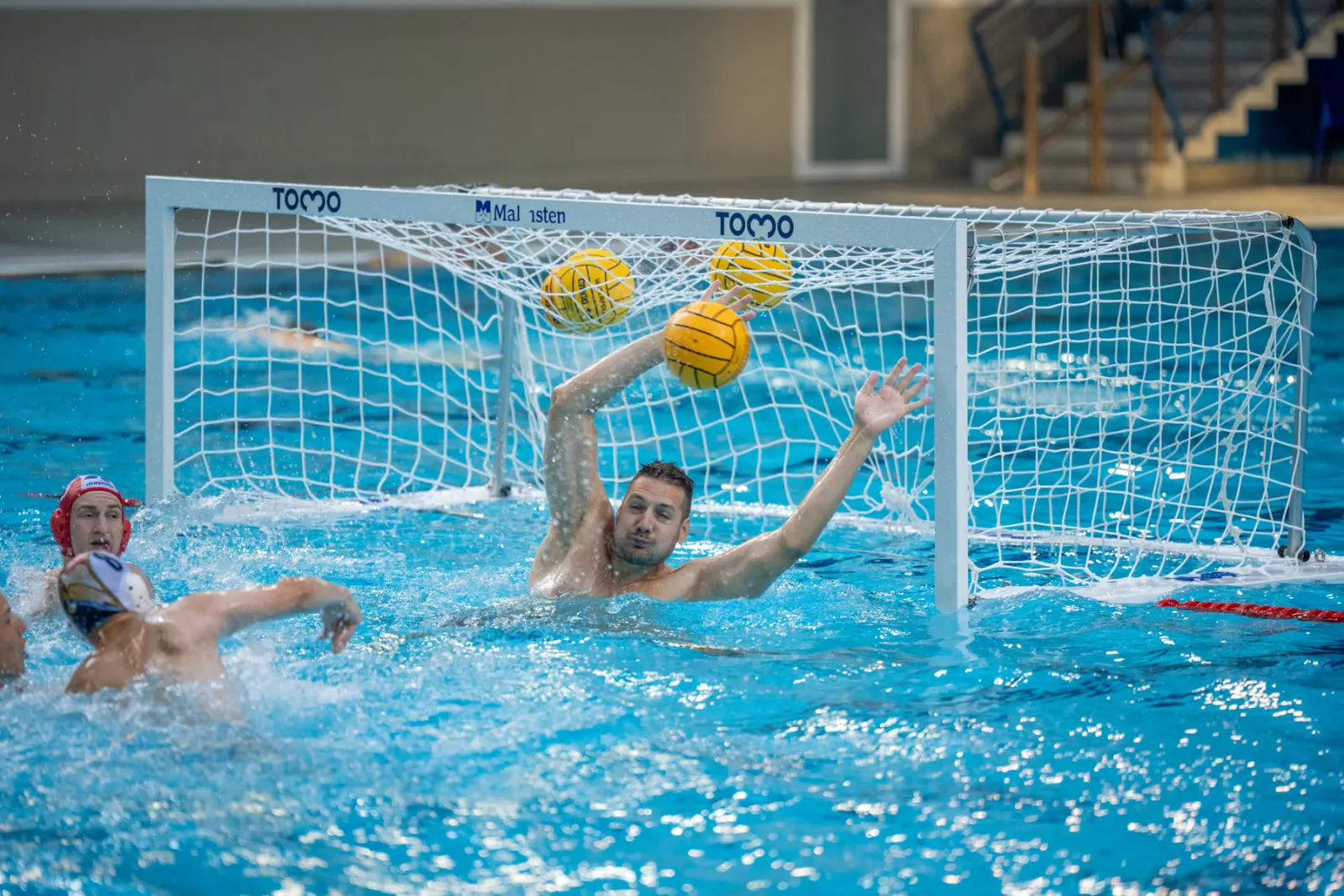 Goalkeeper reaching for a shot with balls in the net